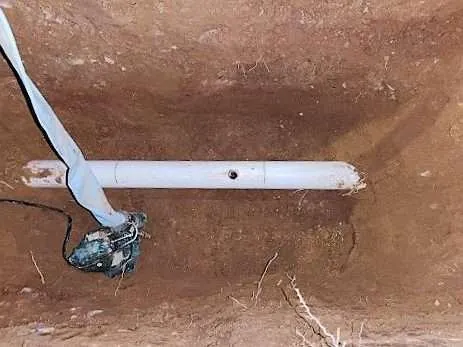 Damaged PVC supply line exposed in a trench